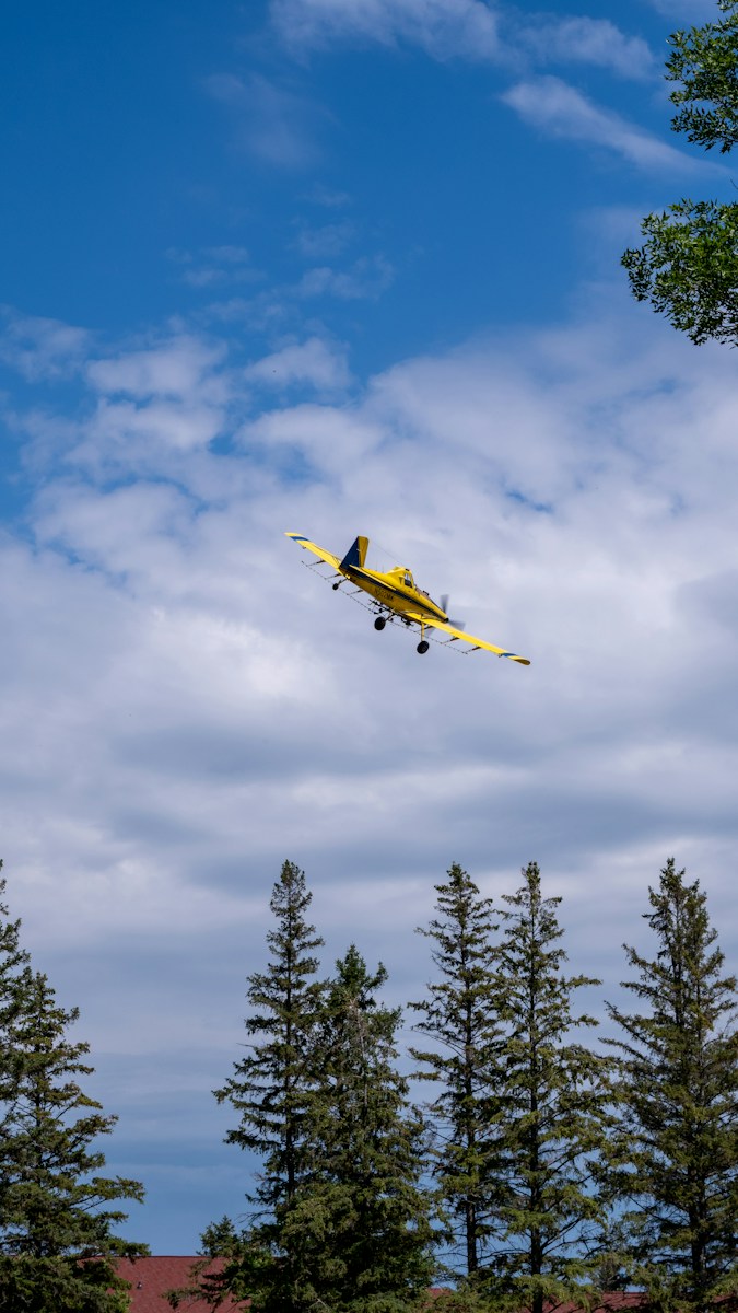 a yellow plane flying through the air